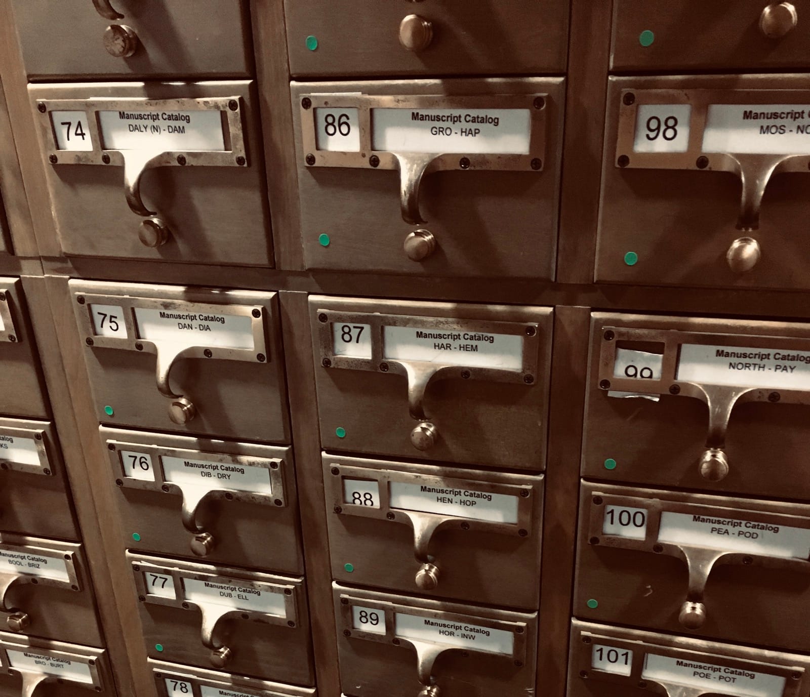 Photo of part of a light brown card catalogue, showing a range of drawers for the Manuscript Catalog.